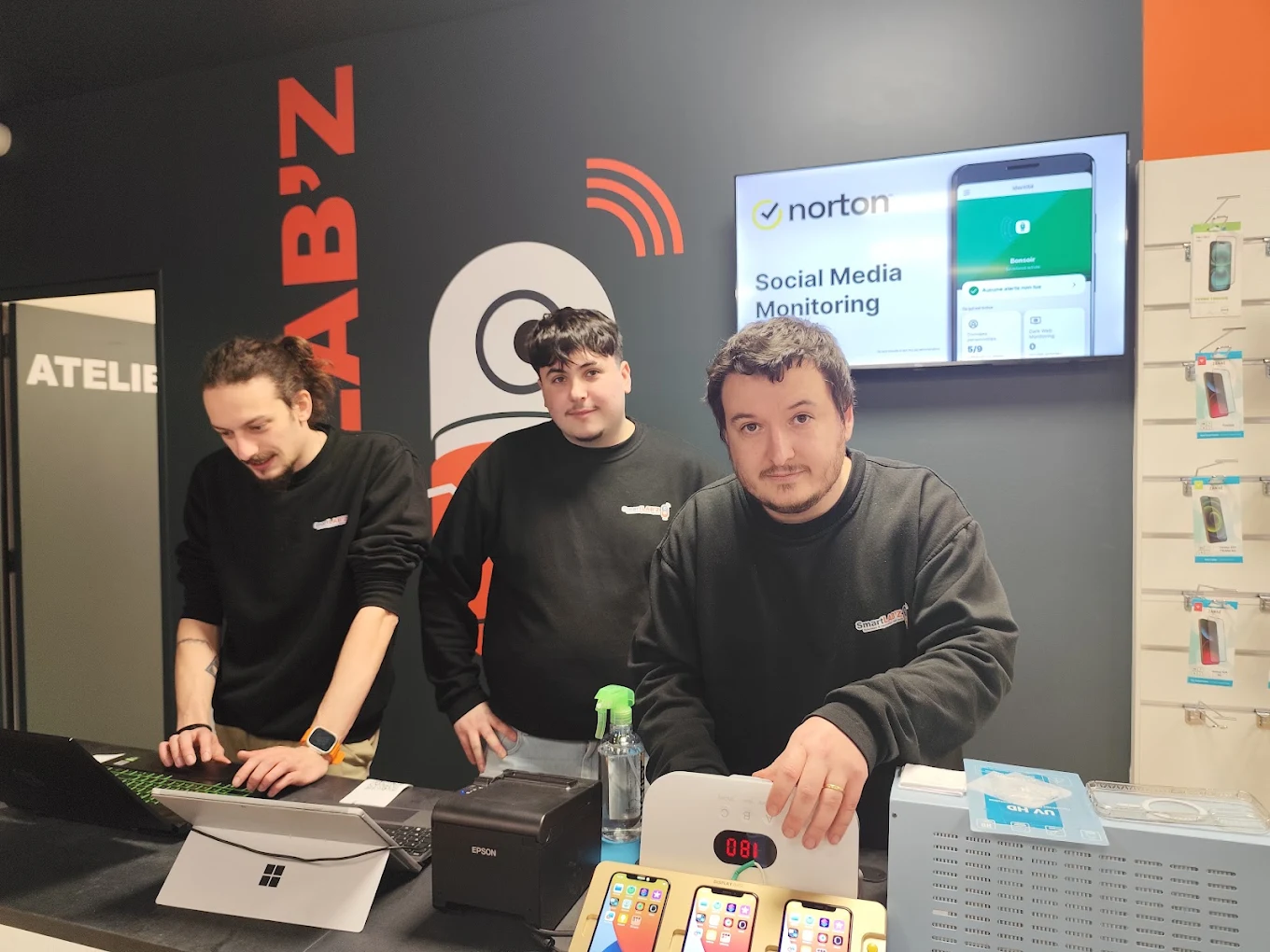 Trois membres de l'équipe SmartLAB'Z derrière le comptoir, devant l'atelier